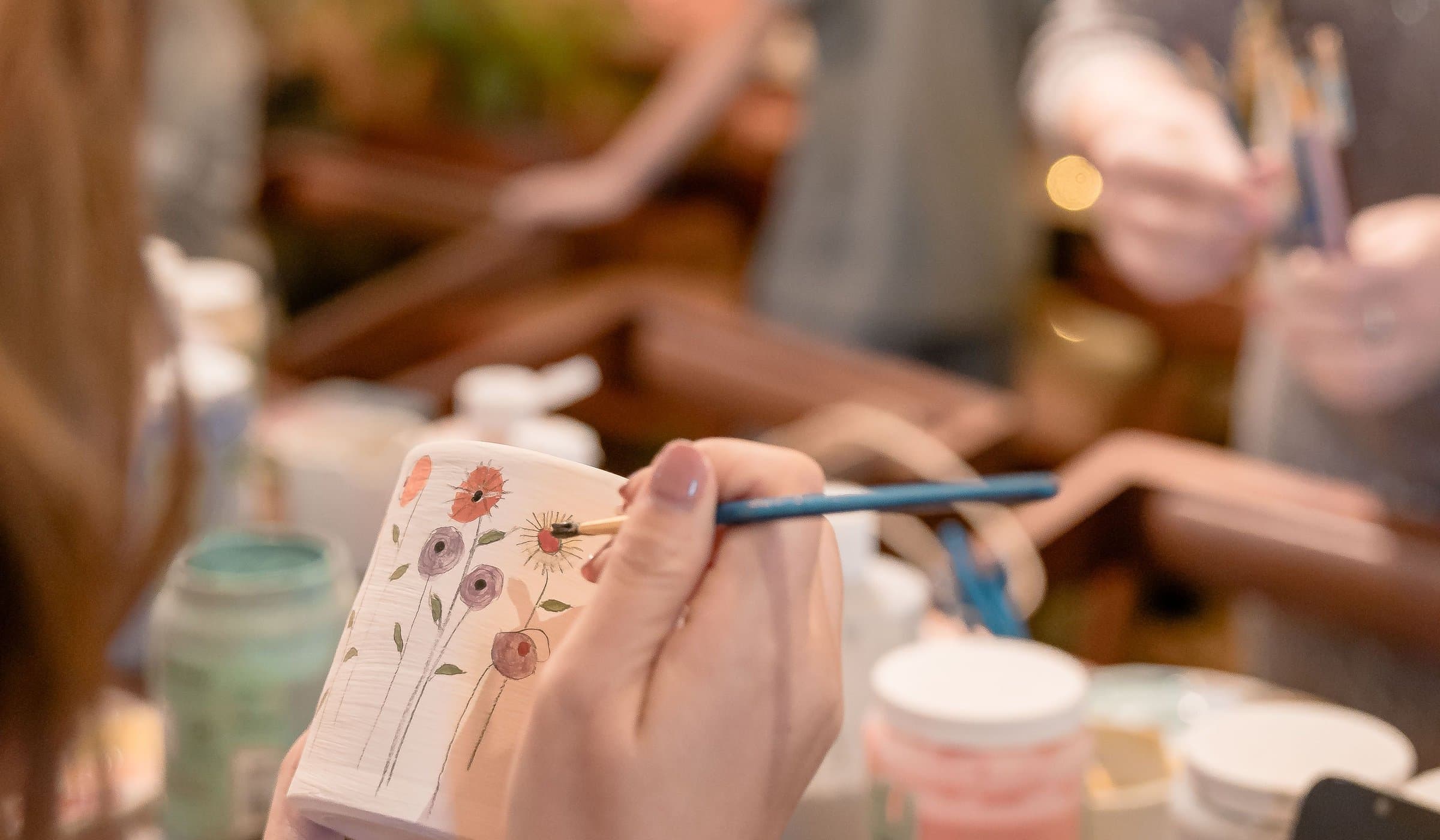 Hand-painting a ceramic mug at a pottery-painting café coming to Century City