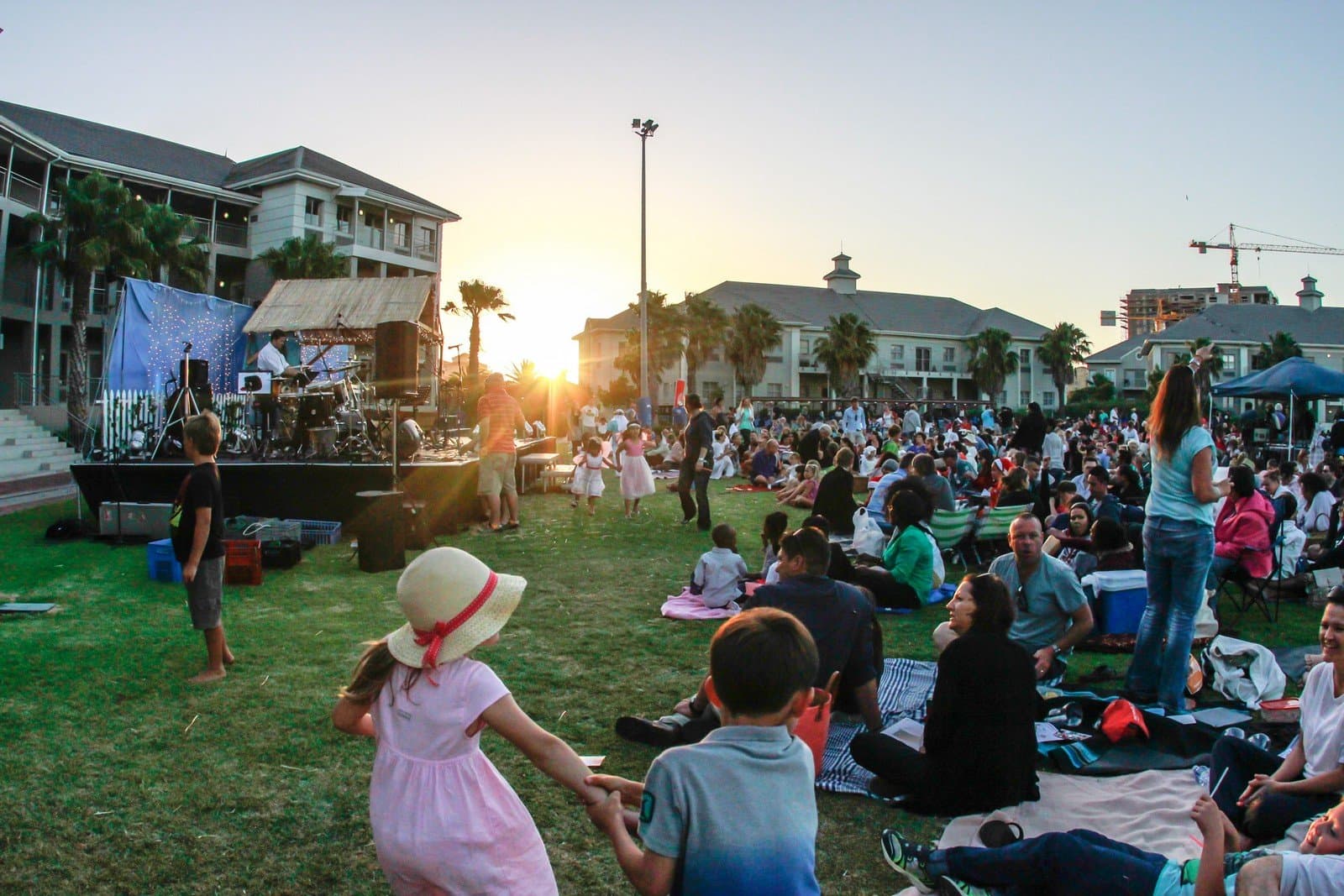 Families on the grass at an outdoor evening event with live music in Century City